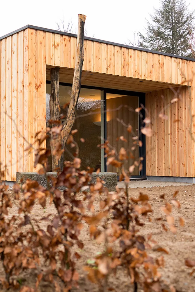 La salle d’Essentiellement Soi vue de l’extérieur, façade en bois nichée dans la verdure à Ovifat